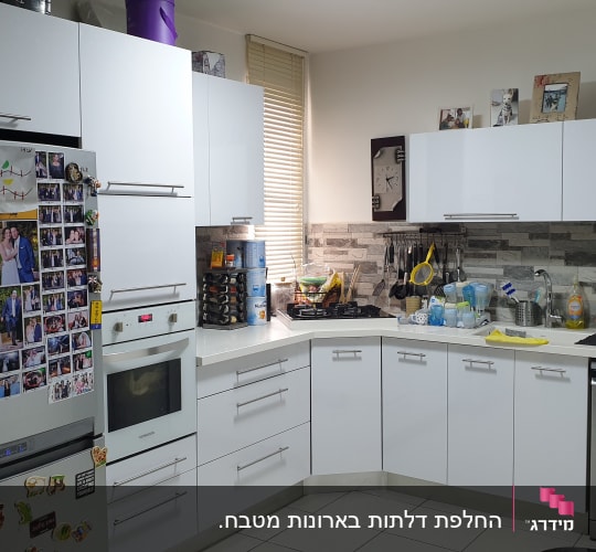 מטבח עם ארונות לבנים, כלים על השיש